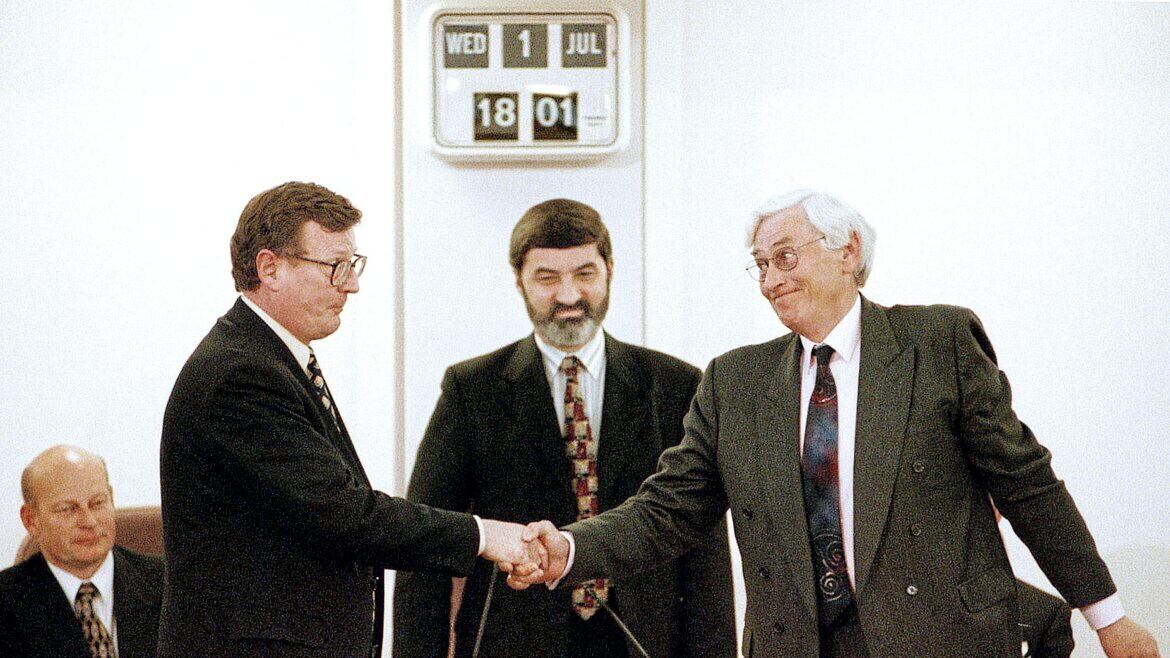 David Trimble and Seamus Mallon shake hands after being elected First and Deputy First Ministers of a new power-sharing government following the signing of the Good Friday Agreement in 1998, with Assembly Speaker Lord Alderdice looking on 
