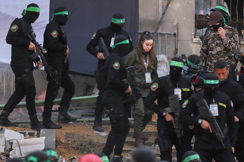 Israeli soldier Agam Berger walks next to masked Islamic Jihad militants as she is handed over to the Red Cross at the Jabalya refugee camp in Gaza City (AP Photo/Mohammed Hajjar)