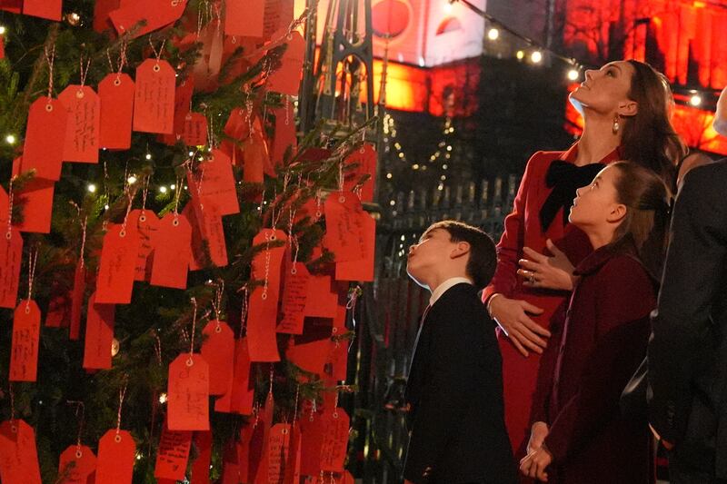 Kate, Charlotte and Louis look at messages on the Kindness Tree