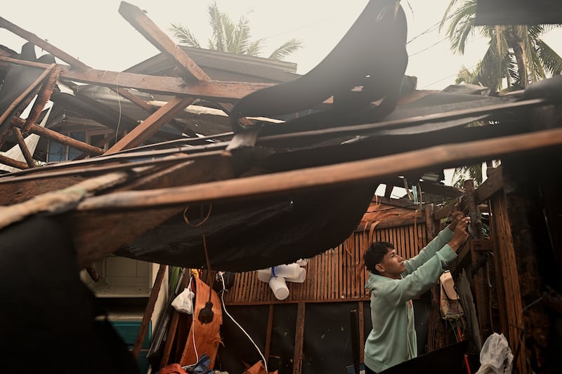 A resident checks belongings from his damaged home in the municipality of Baler (Noel Celis/AP)