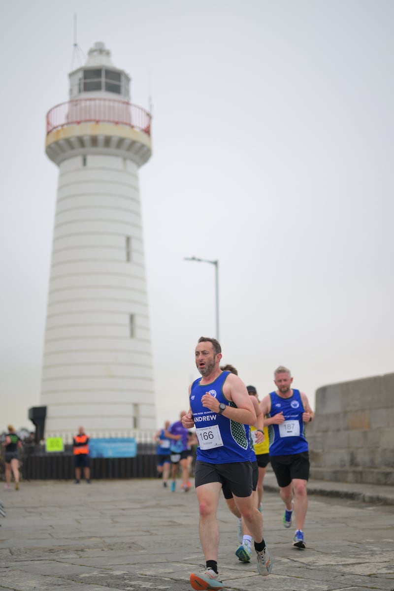 Group of runners in 5k race in front of white lighthouse