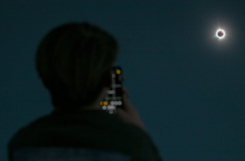 A person in Montral, Canada, takes a photograph of the sun during totality (Graham Hughes/The Canadian Press via AP)