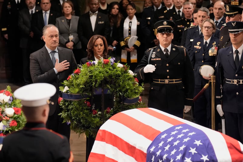 Vice President Kamala Harris, with her husband Doug Emhoff, places a wreath at the flag-draped casket of former President Jimmy Carter during a ceremony at the Capitol (J Scott Applewhite/AP)