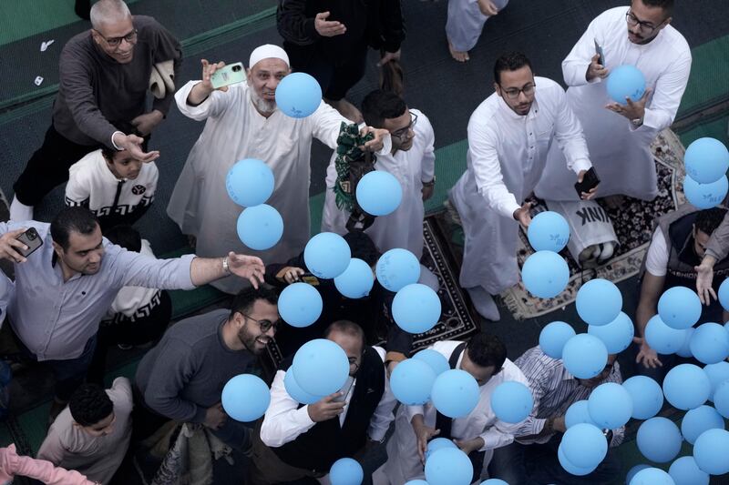 People try to catch free balloons distributed during Eid al-Fitr in Cairo, Egypt (Amr Nabil/AP)