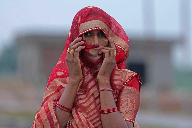A woman watches members of a forensic team investigate the scene a day after a fatal stampede in Fulrai village of Hathras district (Rajesh Kumar Singh/AP)