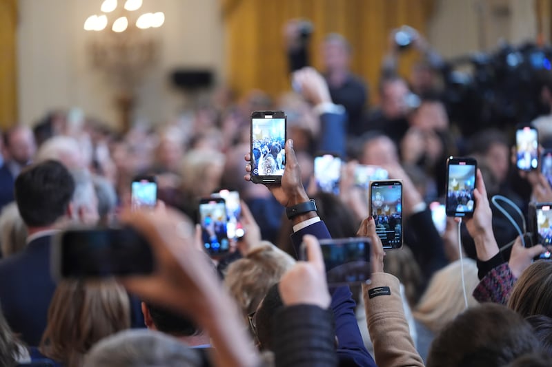 Smartphones photograph Donald Trump before he signs an executive order barring transgender female athletes from competing in women’s or girls’ sporting events (AP)