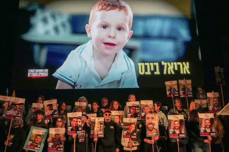 Demonstrators hold portraits of hostages as a video featuring Ariel Bibas, who, along with his parents Shiri and Yarden Bibas, and his brother Kfir, is still being held hostage in Gaza, plays behind them during a protest in Tel Aviv (Ohad Zwigenberg/AP)