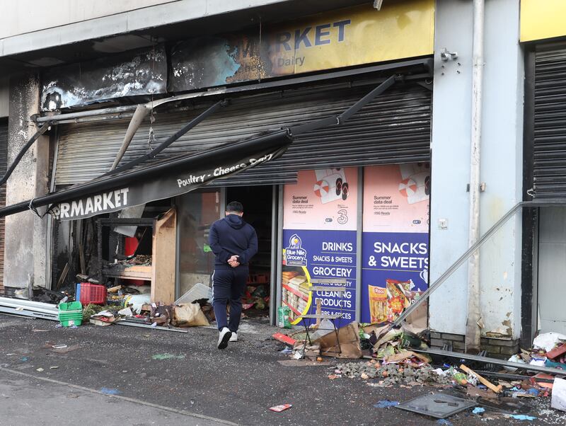 Supermarket owner Abdelkader inspects the damaged after it was set alight for a second time. 
PICTURE COLM LENAGHAN