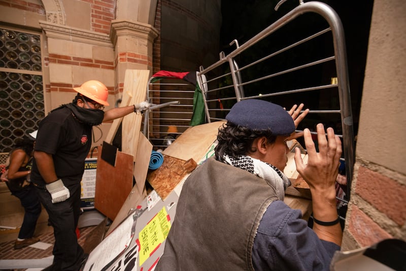 Pro-Palestinian demonstrators watch police activity behind a barricade on the UCLA campus (AP)