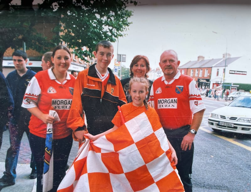 A family photo of the Loughran family from Co Armagh standing in Armagh jerseys and holding orange and white checkered flags