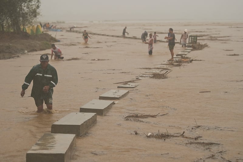 Residents move to safer ground as they evacuate from their homes along a swollen river caused by heavy rains from Typhoon Toraji (Noel Celis/AP)