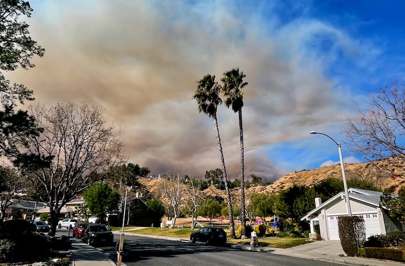 A large plume of smoke rises from Castaic Lake seen behind a neighbourhood in Santa Clarita (Marcio Jose Sanchez/AP)