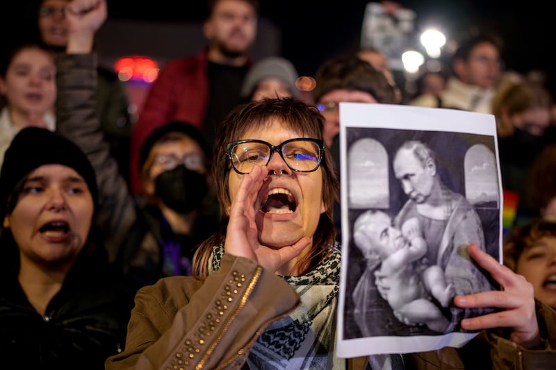 A woman shouts holding an altered version of a classic painting, depicting Russian President Vladimir Putin and Calin Georgescu, the independent candidate for Romanian presidency (AP/Andreea Alexandru)