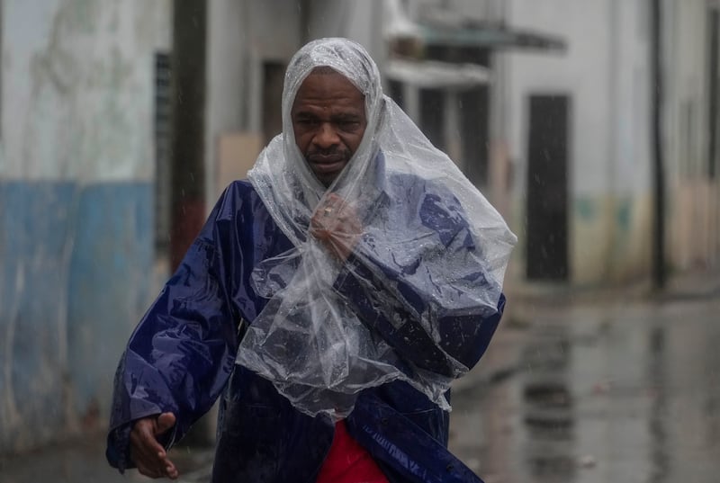 A man walks through the wind and rain (Ramon Espinosa/AP)