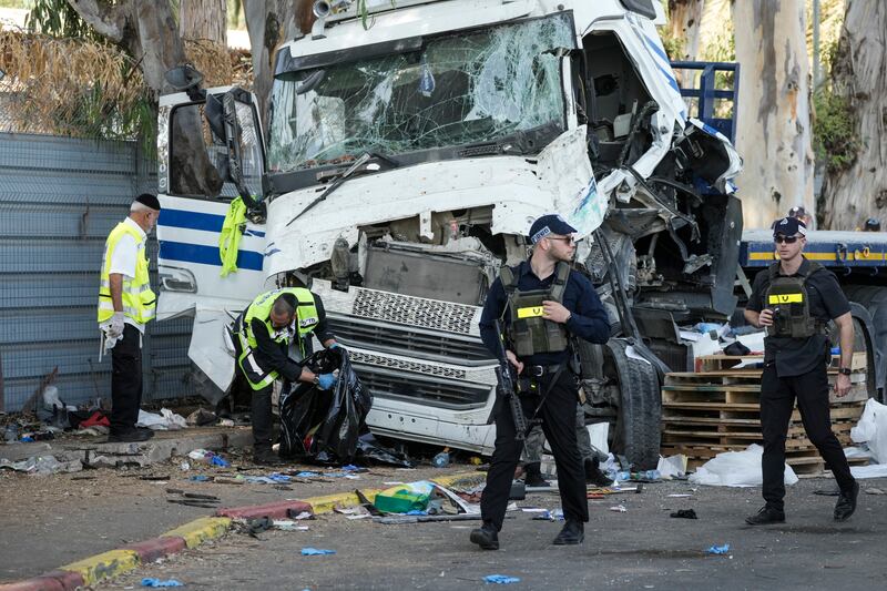 Israeli police and rescue services inspect the site where a truck driver rammed into a bus stop near the headquarters of Israel’s Mossad spy agency in Tel Aviv (Oded Balilty/AP)