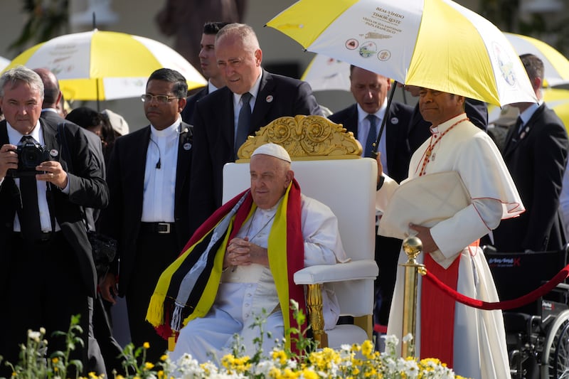 Archbishop of Dili Cardinal Virgilio do Carmo da Silva, right, protects Pope Francis, wearing an East Timor traditional scarf, from the sun with an umbrella in the colours of the Vatican flag (Gregorio Borgia/AP)