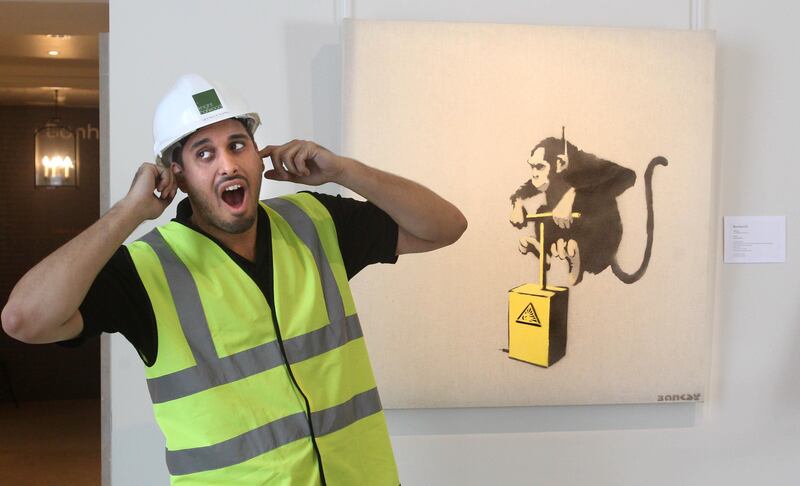 A workman jokes next to Banksy’s Monkey Detonator work