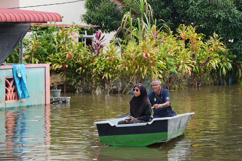 People use a boat to cross a flooded area in Tumpat, on the outskirts of Kota Bahru in Kelantan state on the east coast of Malaysia (Vincent Thian/AP)