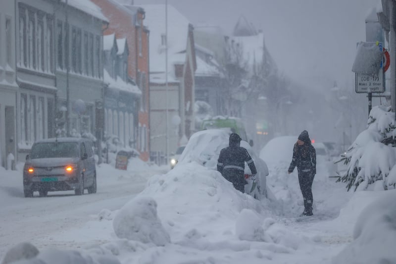 People try to clear snow from cars in Kristiansand, Norway, on Tuesday. (Tor Erik Schroder/NTB Scanpix via AP)