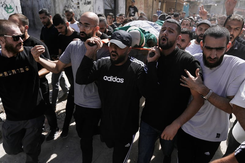 Mourners carry the body of militant Haitham Balidi, draped in the Qassam Brigade flag of the Hamas militant group’s military wing, in Tulkarem refugee camp in the West Bank (Majdi Mohammed/AP)