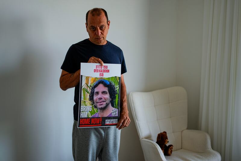 Nissan Kalderon poses in Ramat Gan, Israel, with a photo of his only brother, Ofer Kalderon (Ariel Schalit/AP)