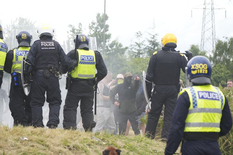 Scott Greenwood (centre, with yellow face covering and bucket hat) was at the forefront of a group confronting riot police .