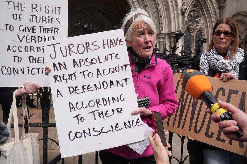 Trudi Warner holding the sign outside the Royal Courts of Justice in London