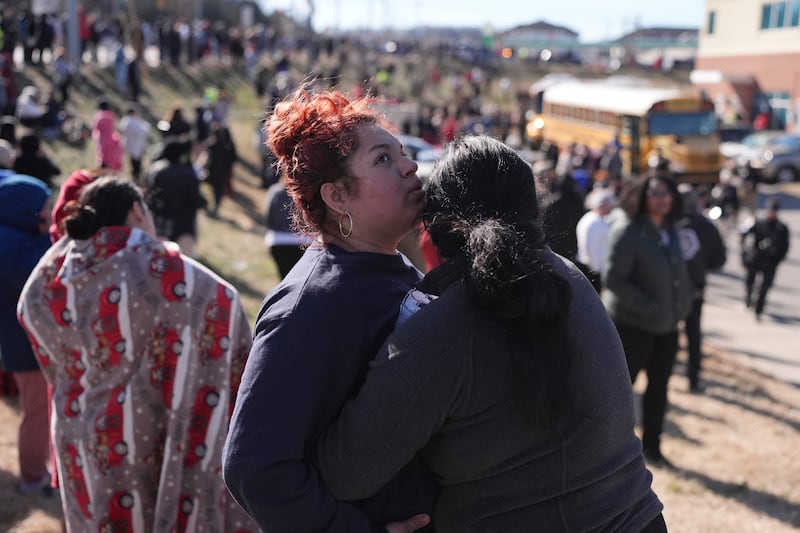 Families wait as school buses arrive outside the school (George Walker IV/AP)