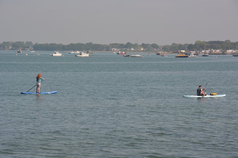 Paddle boarders enjoy calm conditions in Langstone Harbour in Portsmouth, Hampshire