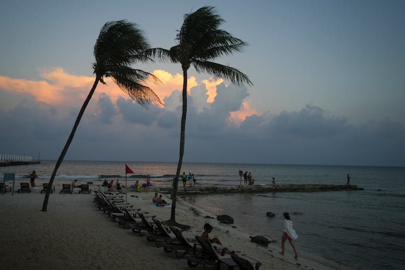 People lounge on the beach as the sun sets ahead of Hurricane Beryl’s expected arrival in Playa del Carmen, Mexico (Fernando Llano/AP)