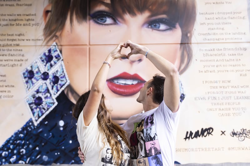 Fans Giorgia Zampetti, left, and Tommaso Zampetti, from Italy, pose in front a new mural that has been created to celebrate Swift’s arrival in the capital