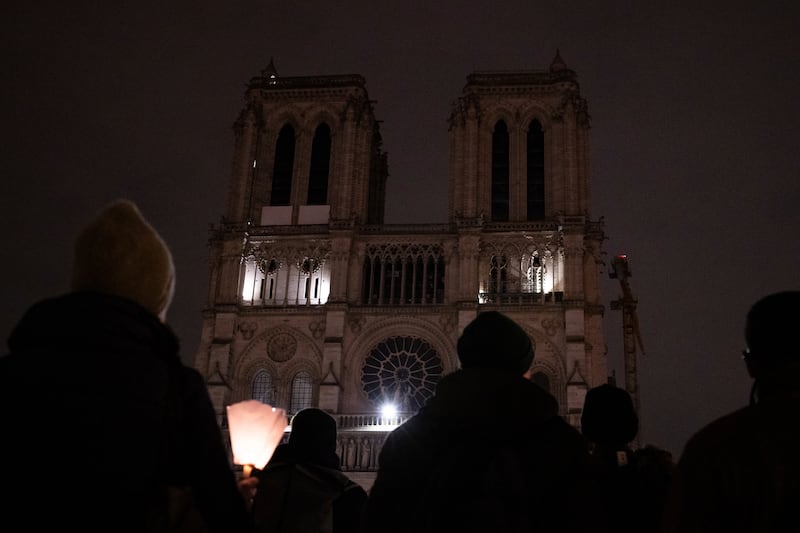 People watch Notre Dame Cathedral after a procession to bring the Virgin Mary statue from Saint-Germain l’Auxerrois church to the cathedral in Paris (Louise Delmotte/AP)