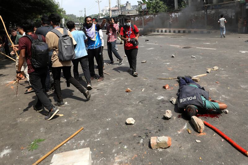 An injured policeman lies on a street during clashes with students in Dhaka, Bangladesh (Rajib Dhar/AP)