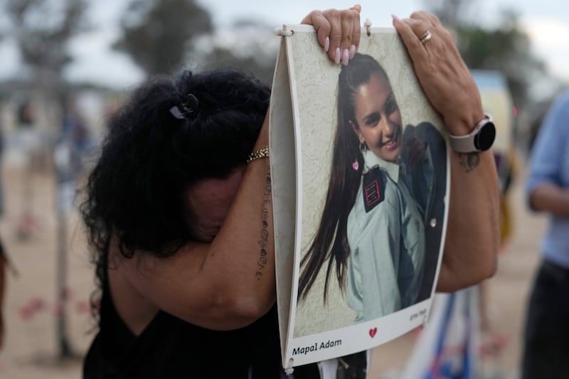 A woman leans on a picture of Mapal Adam, at the site of the Nova music festival (Ariel Shalit/AP)