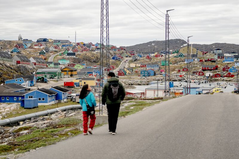 People walk in the town of Aasiaat in western Greenland (Ida Marie Odgaard/AP)