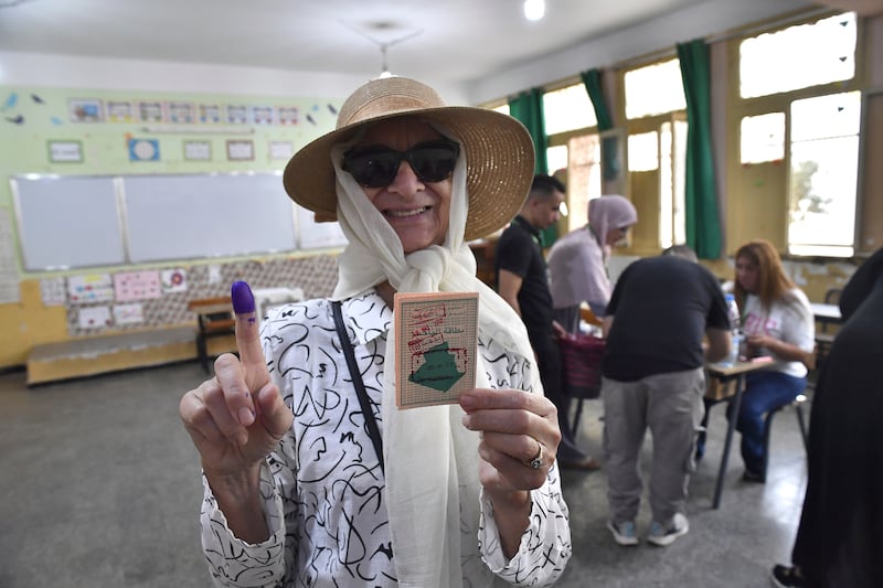 A voter poses for a photo with her inked finger after casting her ballot (Fateh Guidoum/AP)