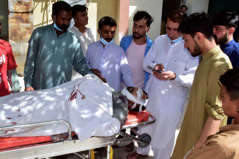 Relatives gather around the body of a passenger who was killed by gunmen on a highway in Musakhail (Arshad Butt/AP)