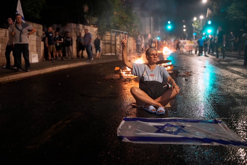 A demonstrator sits on the street in Jerusalem during a protest against Israeli Prime Minister Benjamin Netanyahu’s government on Monday (Ohad Zwigenberg/AP)