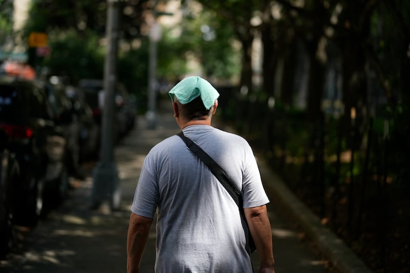 A man wears a damp towel on his head during a hot day in New York (AP)