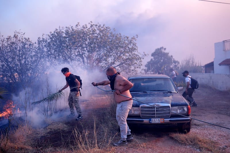 Volunteers worked to extinguish flames near a house in northern Athens (Aggelos Barai/AP)