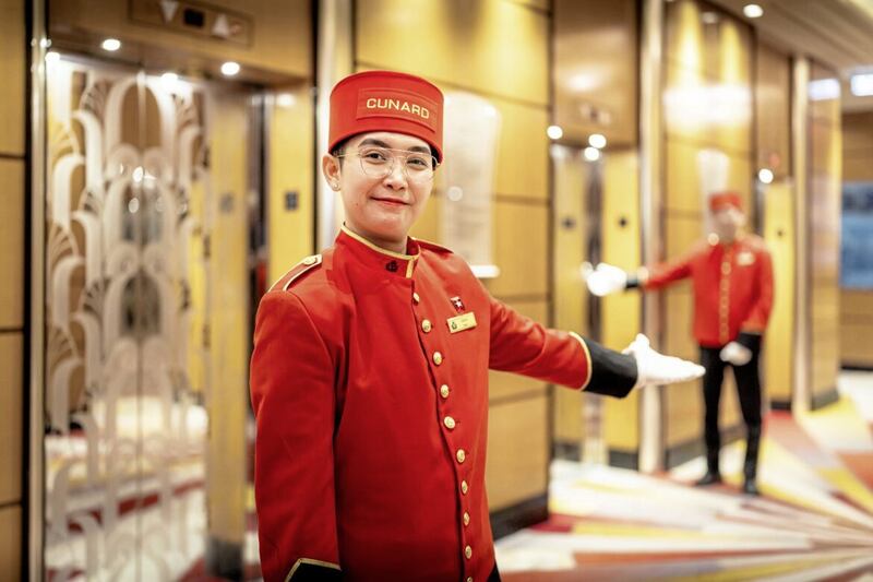 A female Bellhop welcomes passengers during embarkation on board Queen Mary 2.Client: Cunard.Picture date: Sunday November 13, 2022.Photograph by Christopher Ison &copy;07544044177chris@christopherison.comwww.christopherison.comIMPORTANT NOTE REGARDING IMAGE LICENCING FOR THIS PHOTOGRAPH: Agreement title: For Cunard and third parties - Chris Ison photographyAgreement: This image is for Cunard and third parties, can be used in all markets, all channels and expires on 1 November 2027.  No sales are permitted unless expressly agreed in writing with the photographer. 