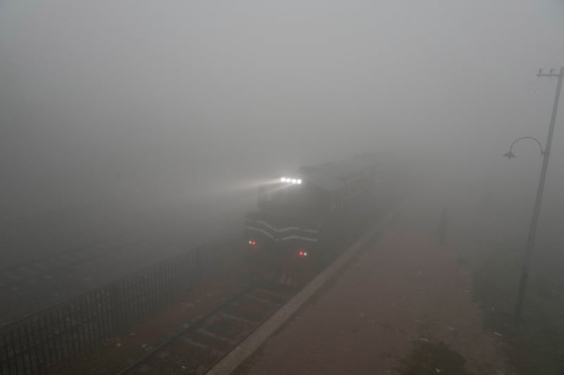 A commuter train’s headlights can just be seen as smog envelops an area of Lahore, Pakistan (KM Chaudary/AP)