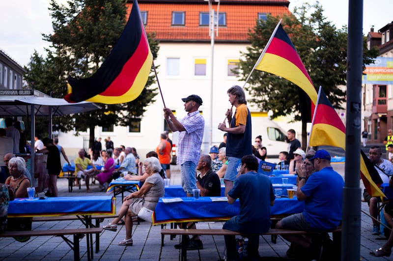 Supporters of the far-right Alternative for Germany party, or AfD, hold German national flags as they attend an election campaign rally (Markus Schreiber/AP)