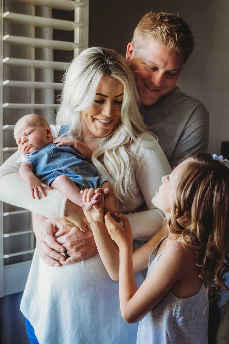 Young mum and dad in nursery with new baby and young daughter