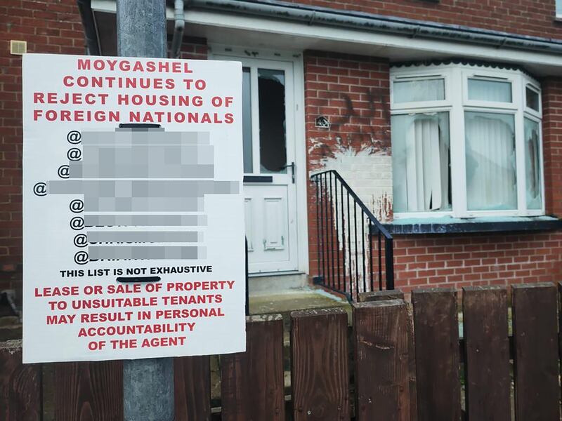 A racist poster outside a home in Co Tyrone with its windows smashed and graffiti sprayed on the walls.
