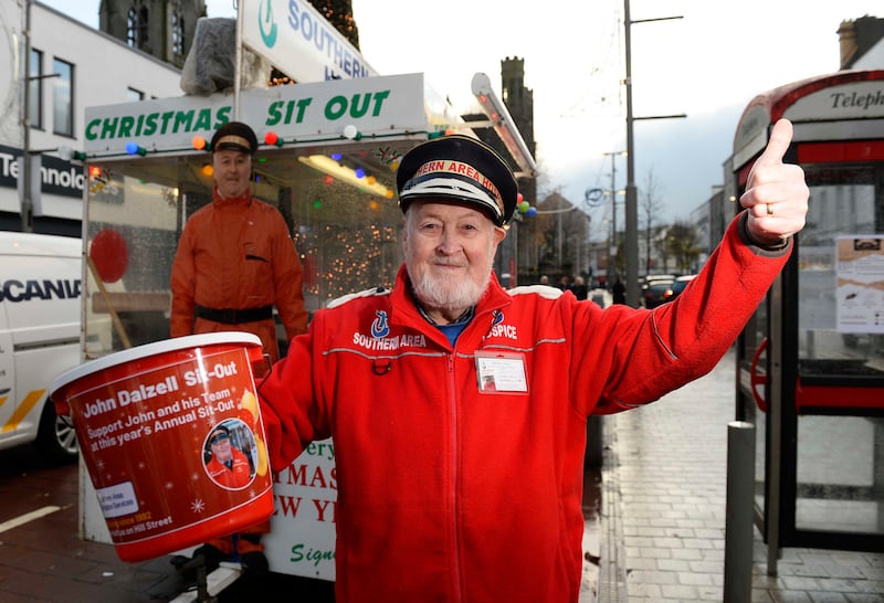 Octogenarian John Dalzell stands out in Newry's Hill Street dressed in a bright red coat and cap. He is fundraising for the Southern area hospice collecting money in his red bucket, smiling and giving a thumbs up