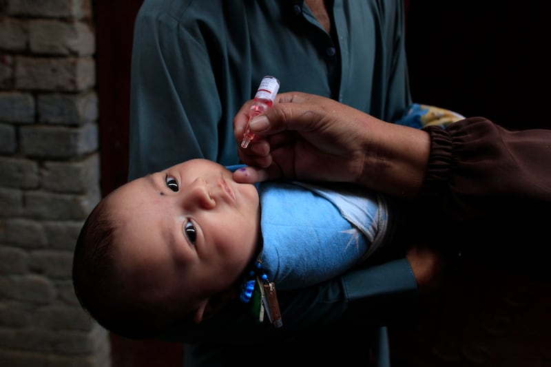 A health worker administers a polio vaccine to a child in a neighbourhood of Peshawar, Pakistan (AP Photo/Mohammad Sajjad)