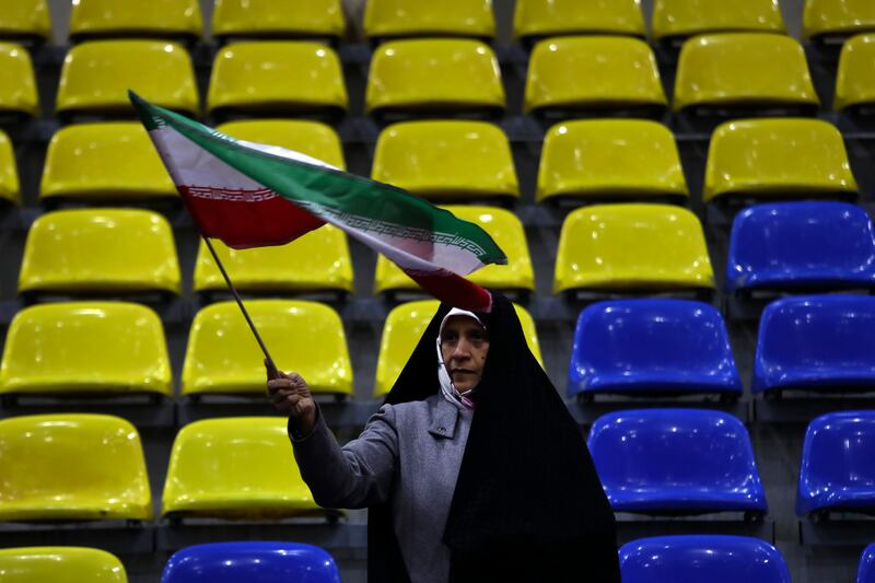 A woman waves an Iranian flag during an election campaign rally (Vahid Salemi/AP)