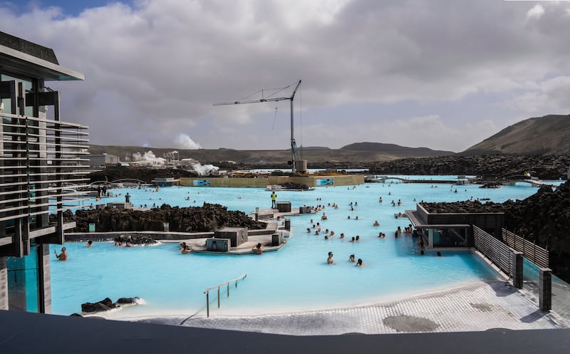 The volcano looms in the distance over the Blue Lagoon (Marco di Marco/AP)