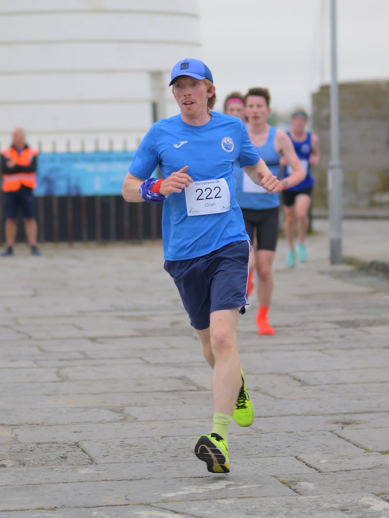 Group of runners in 5k race in front of white lighthouse